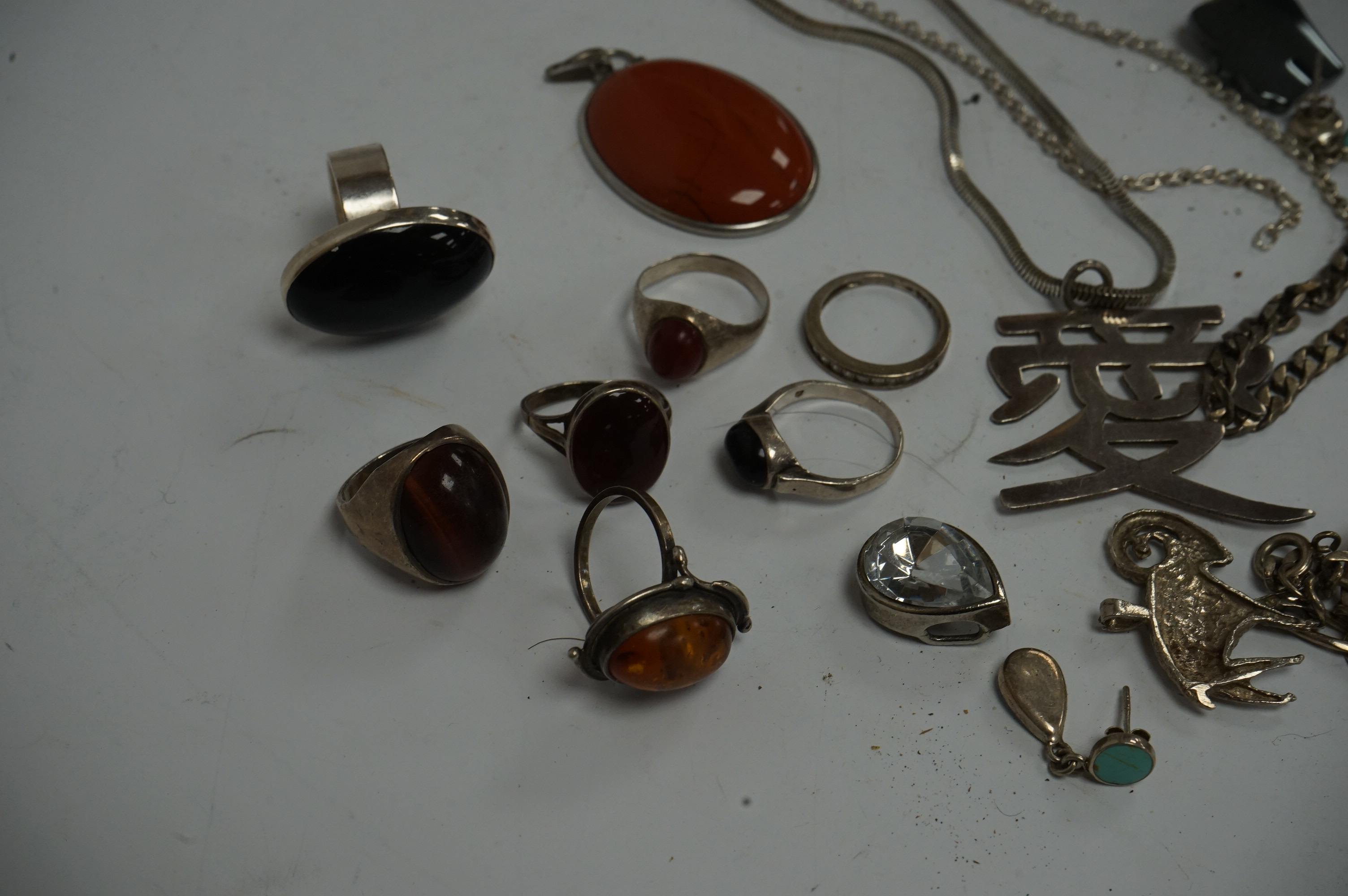 A small collection of assorted jewellery, including silver and 925 rings set with cabochon stones, a child's 925 bangle, amber jewellery, 925 necklace, etc, housed in an inlaid and cross banded box. Condition - poor to f